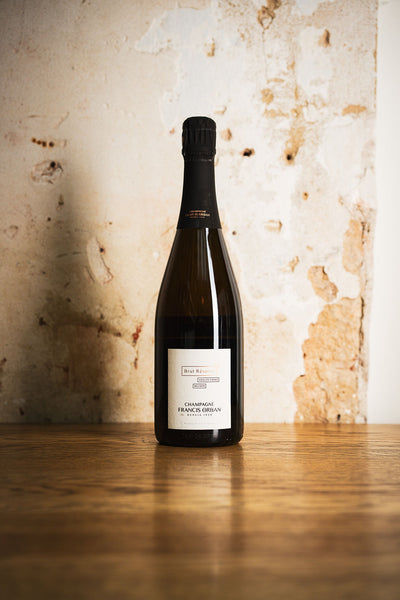 Brut Réserve vieilles vignes champagne bottle on a wooden table against a textured wall.